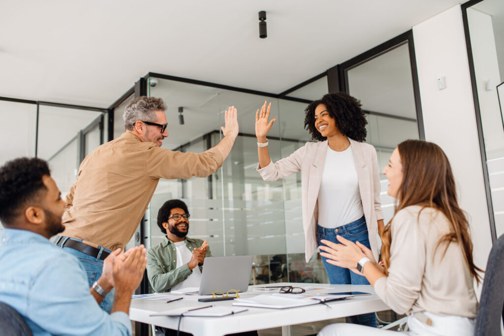 two team members celebrating with a high five while rest of the group cheers